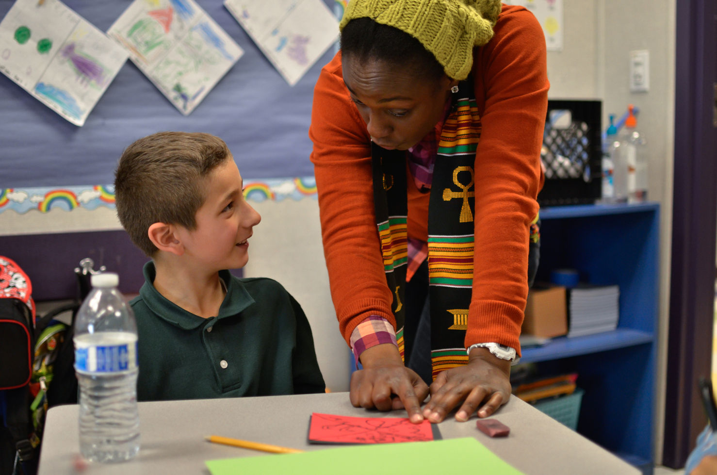 Ms. Solomon points out an interesting pattern on a student's kente square.
